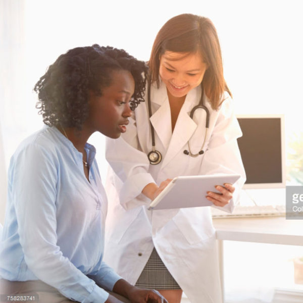 young black woman looking at report by female doctor