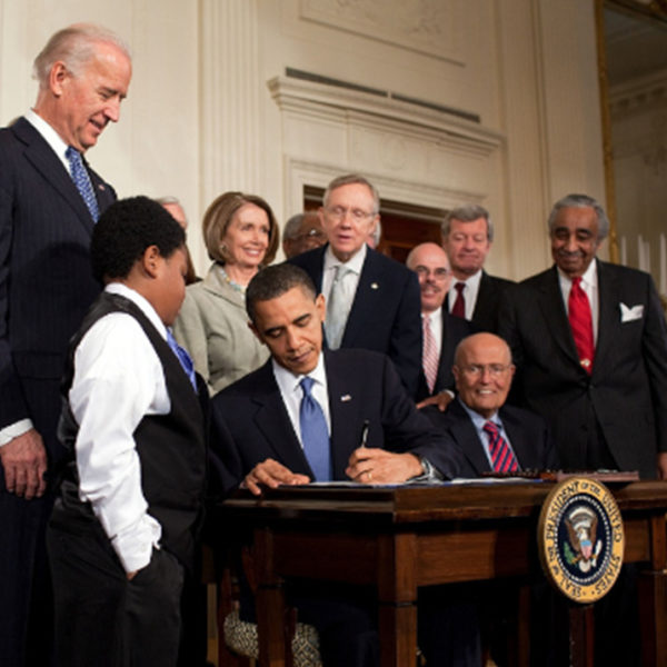 obama signing contract beside young boy and joe biden behind him