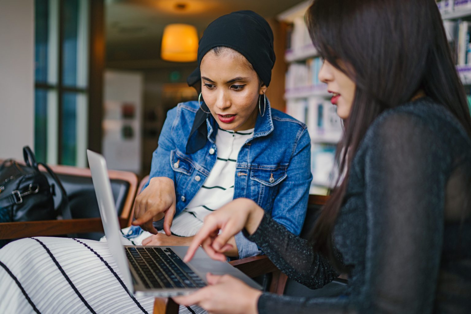 two-women-looking-and-pointing-at-macbook-laptop-1569076 (1)